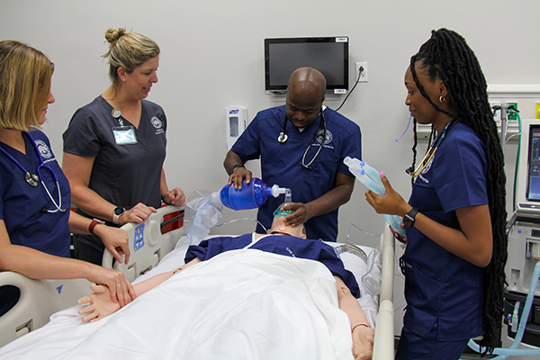 Male and female students practice respiratory care skills on a high-fidelity medical maniken