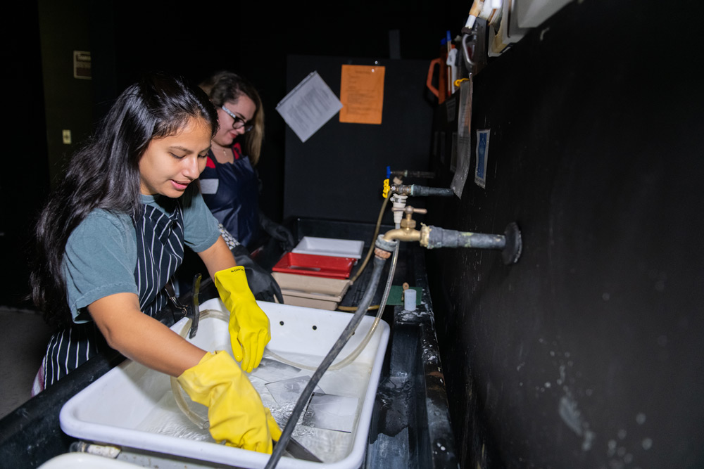 Photography students rinsing prints  in Jacksonville University’s Black and White analog darkroom. 