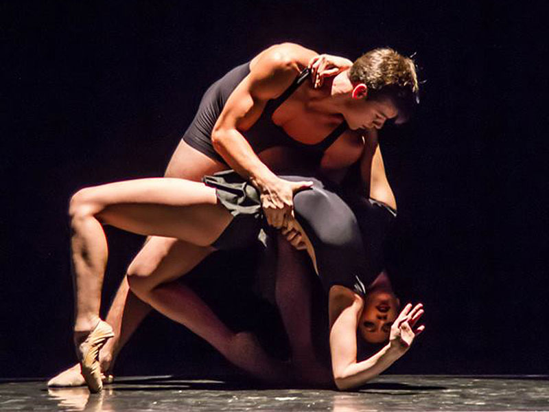 Two students -- one male and one female -- dancing in a performance on stage.