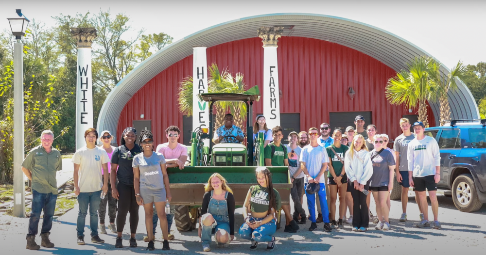 Students and workers standing in front of White Harvest Farms, smiling