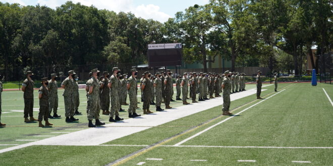 NROTC students dressed in army gear standing at attention on JU football field