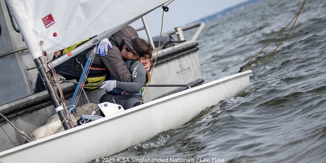A female student sailor hugging her coach on a sailboat after her win.