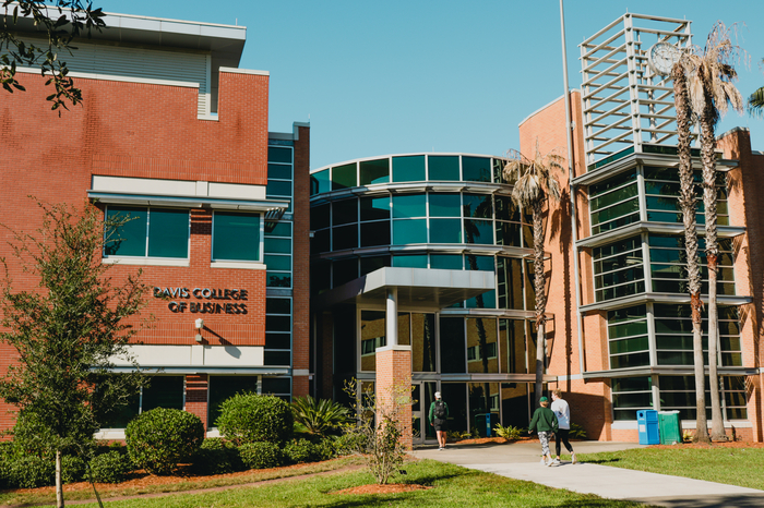 A student standing in front of the Davis College of Business & Technology.