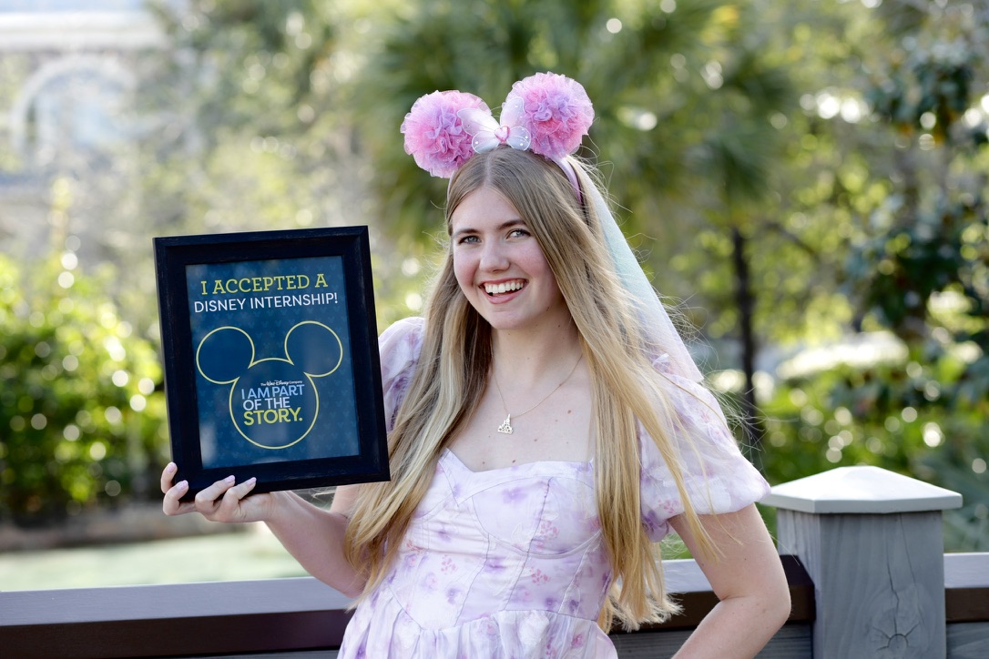 Student Skye Tiedemann holding a poster that signifies her acceptance into a design internship at Disney