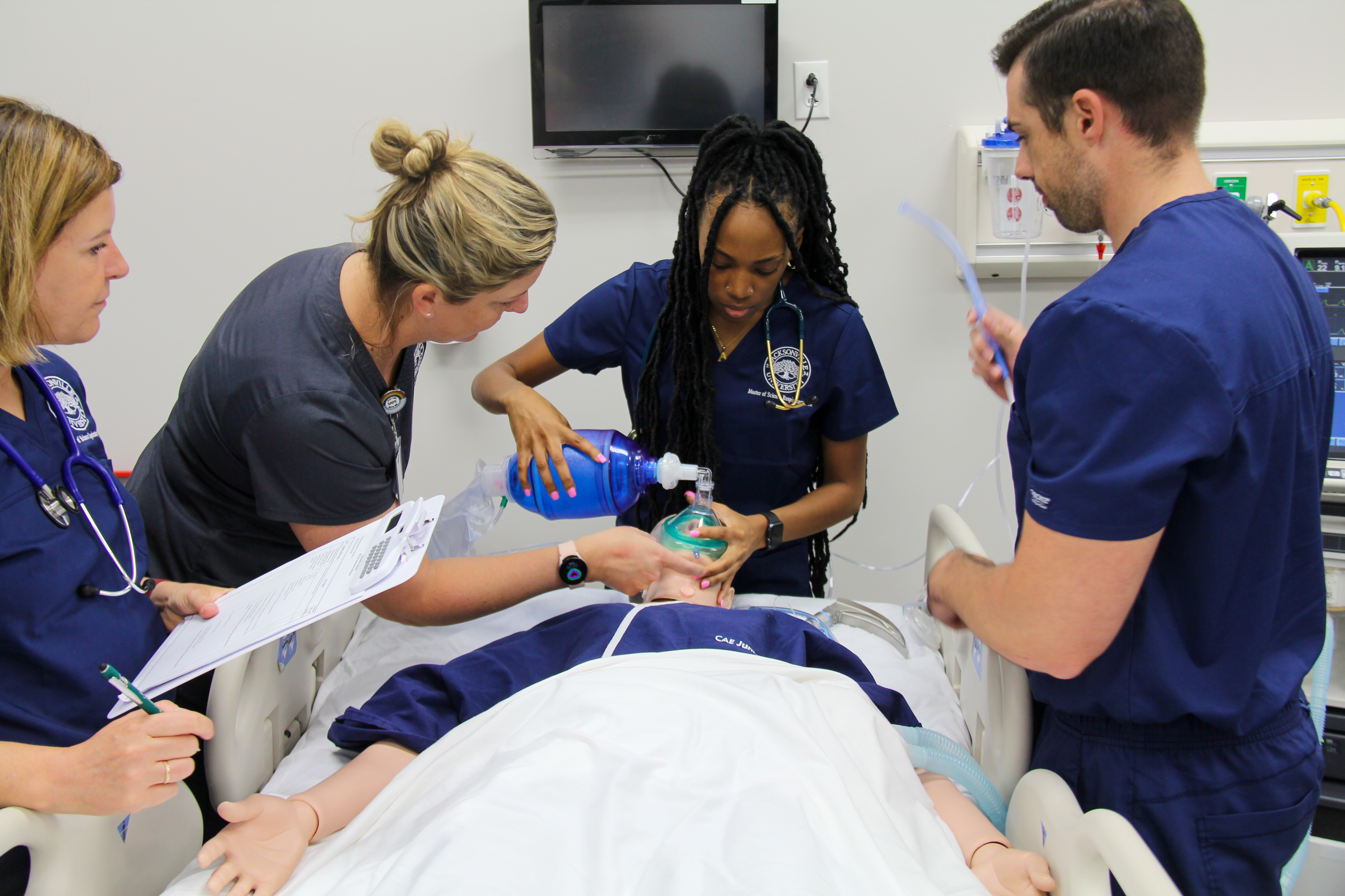A team of respiratory therapists using a respiratory device on a model patient.
