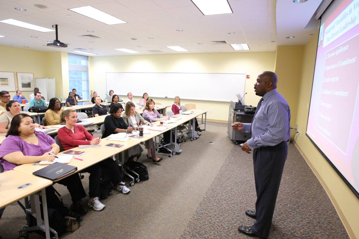 Teacher instructing older students at the front of a classroom