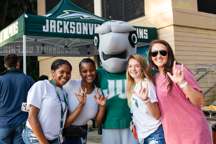 Four students posing with the mascot, Dunkin. 