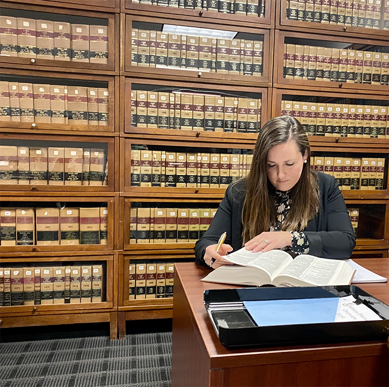 Professional woman in library at courthouse reading a law textbook
