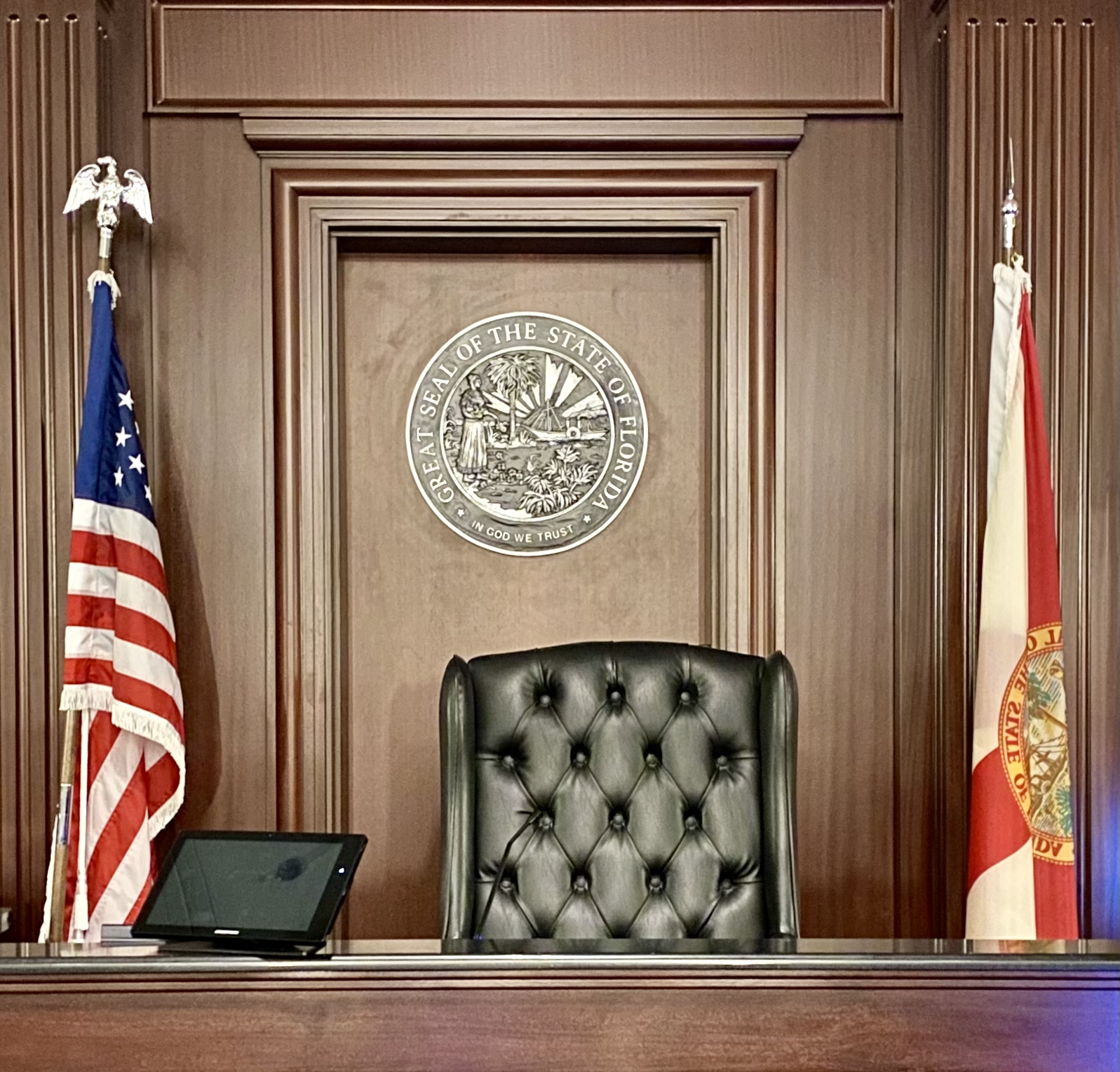 Judges chair in courthouse chamber flanked by United States flag and State of Florida flag