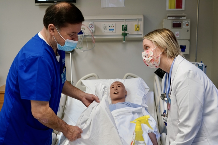 A male and female nurse perform a simulation on a medical maniken