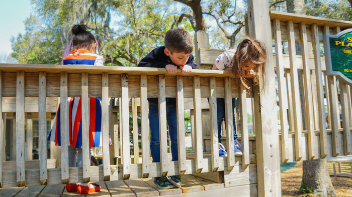 Three children playing on a jungle gym