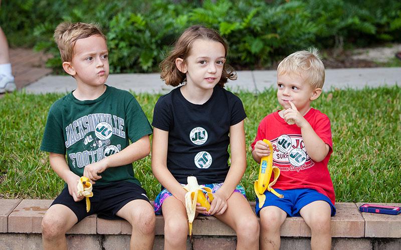 Three children snacking on bananas at the River House