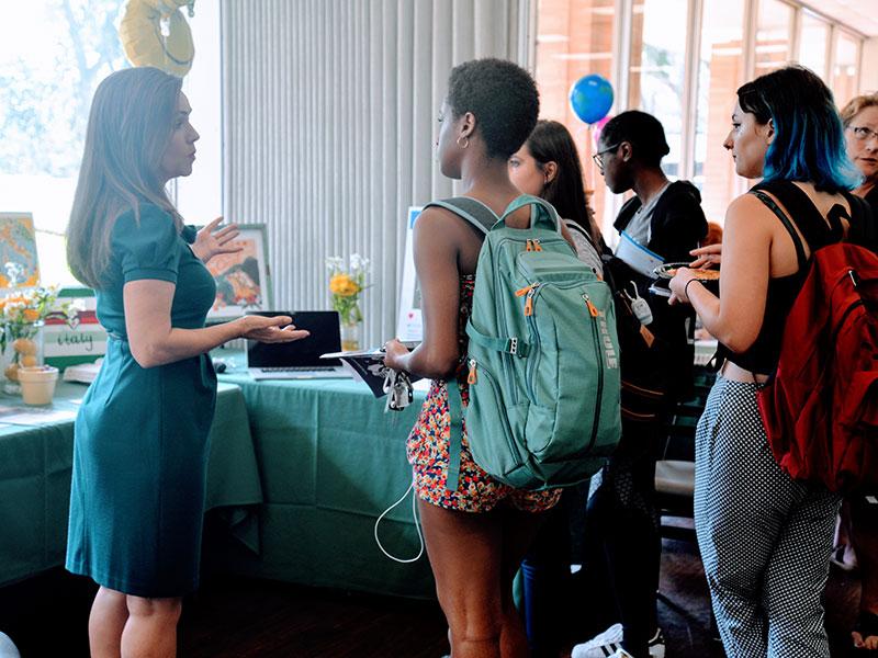 A group of students get information about study abroad from a faculty member.