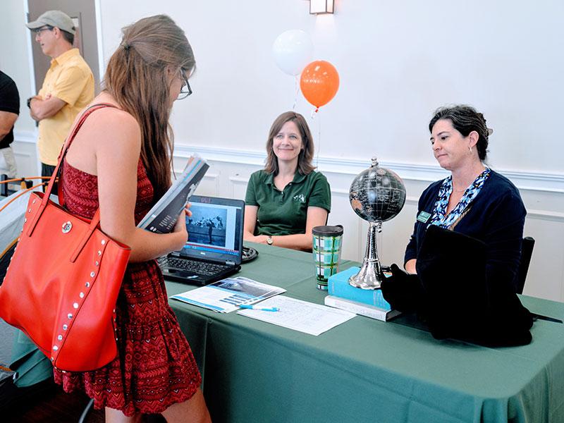 A student gets information about study abroad while two faculty members look on.