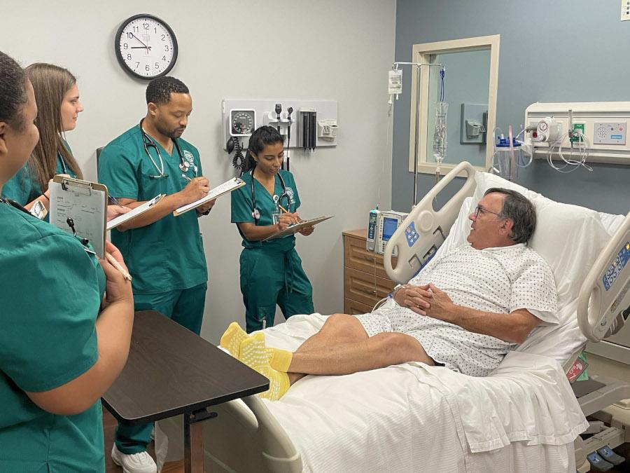 Nursing students gather around a patient care simulation