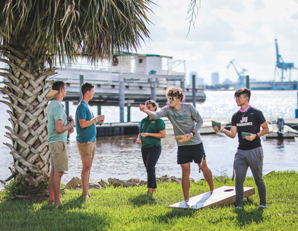 Students playing corn hole on the riverfront.