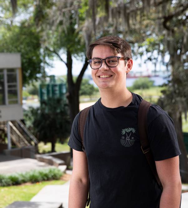 Jacksonville University Student smiling with campus in the background.
