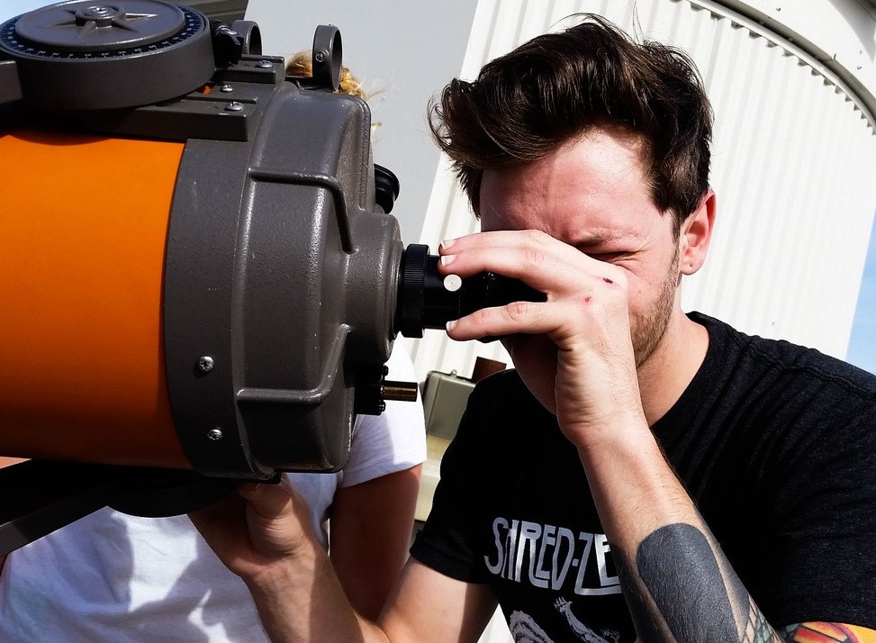 Main looking into a telescope.