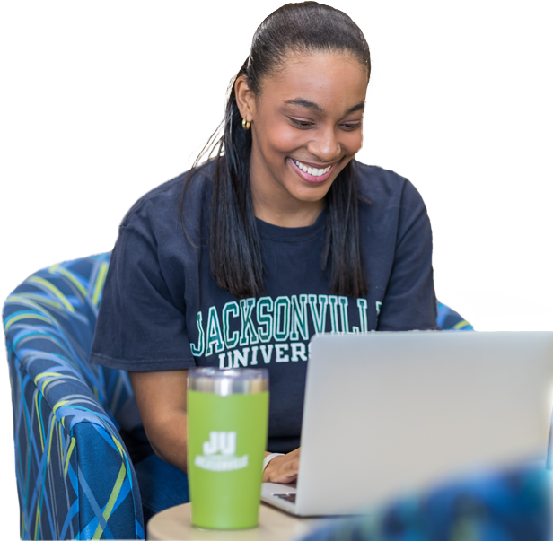 A smiling young woman sitting, using a laptop.