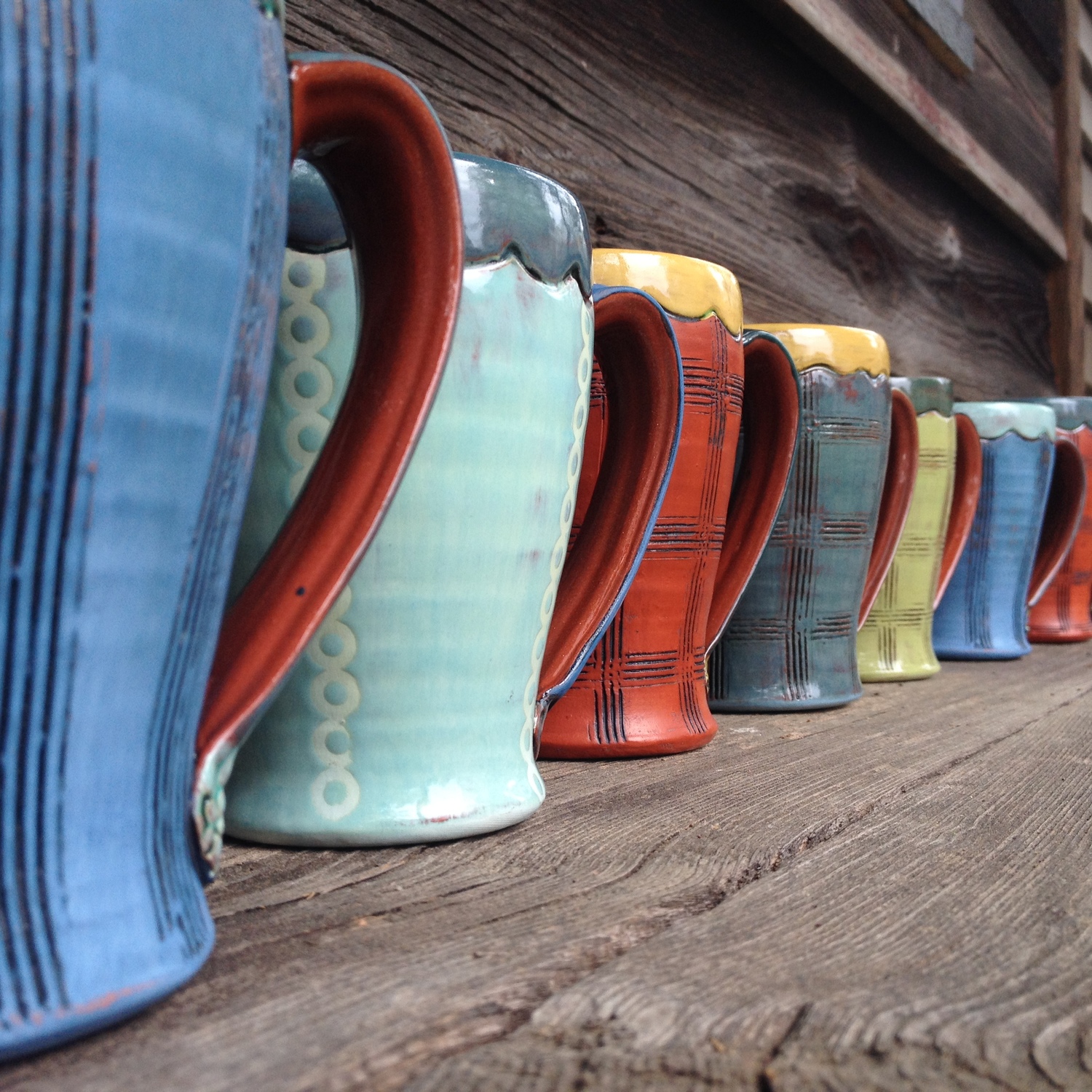 Row of vibrant colored ceramic coffee mugs created by artist Amy Sanders.