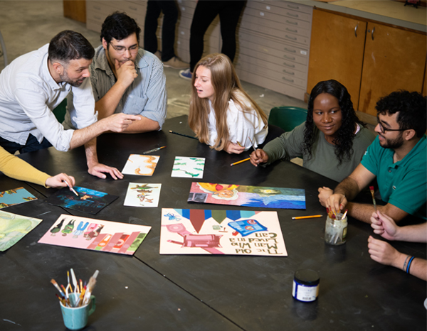 A studio classroom at Jacksonville University featuring students and a professor critiquing illustration work.