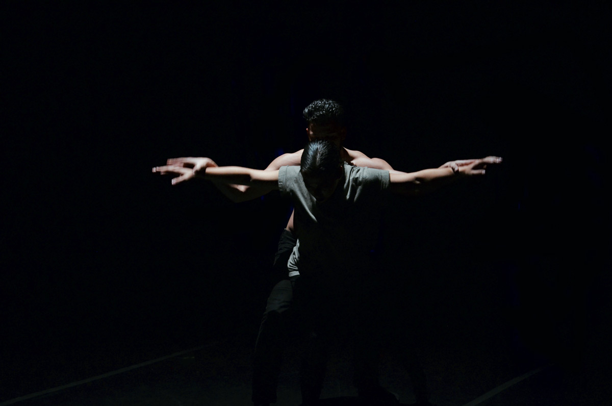 Two Jacksonville University dancers embracing on stage under the spotlight