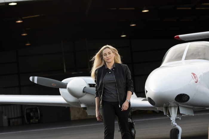 An aviation student standing in front of an airplane.