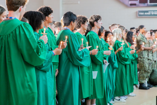 Students standing and carrying candle sticks at matriculation ceremony