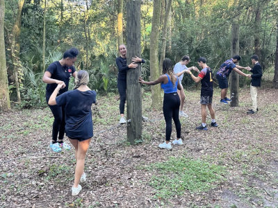 Students in wood trail enlacing their hands around trees