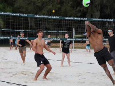 A group of young people playing beach volleyball