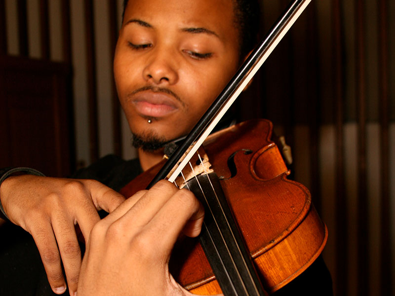 A student playing music on a violin.