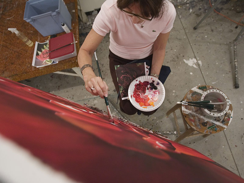 An overhead shot of a student painting on a large canvas.