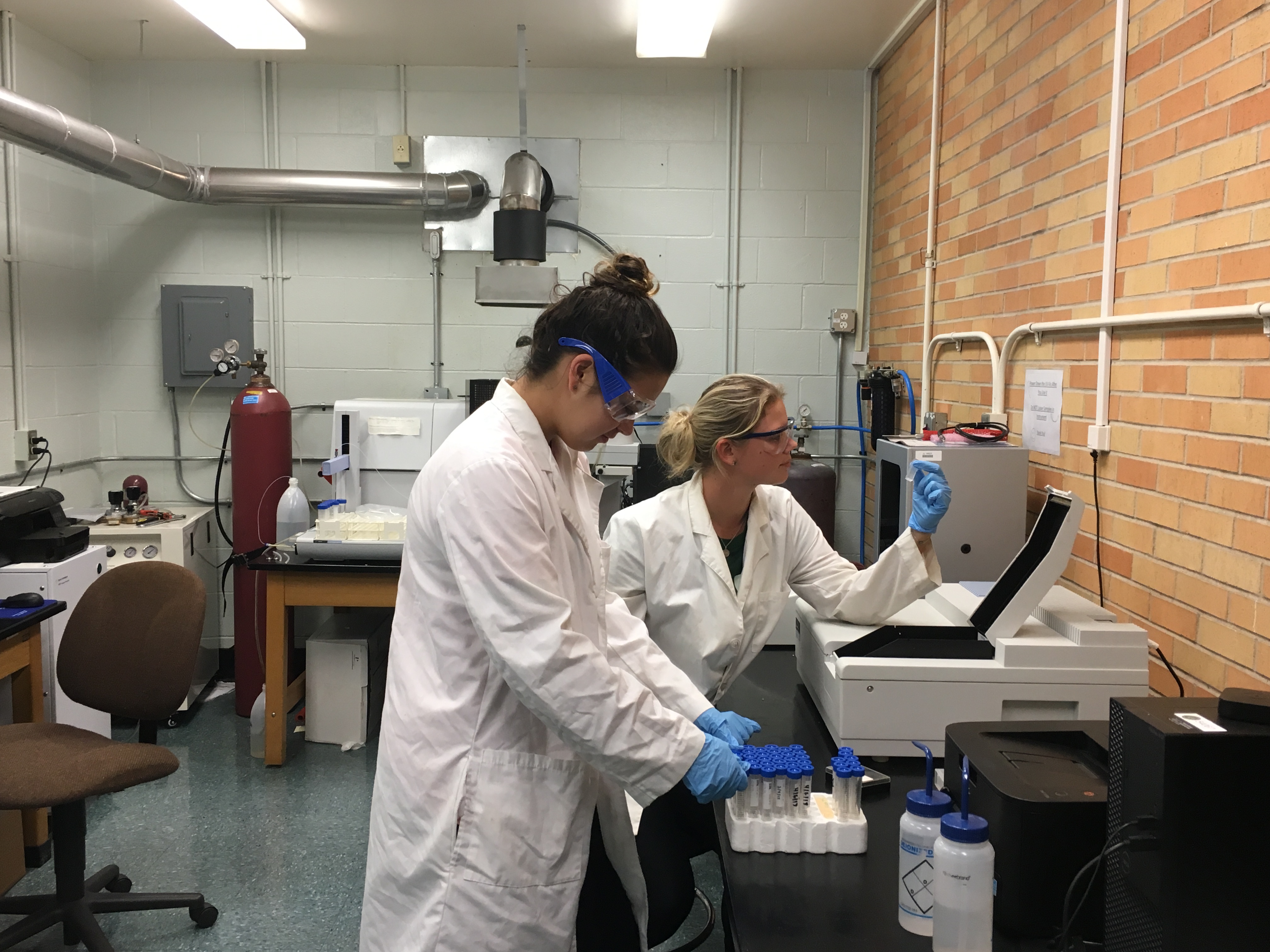 Two female lab technicians working on a lab bench. 