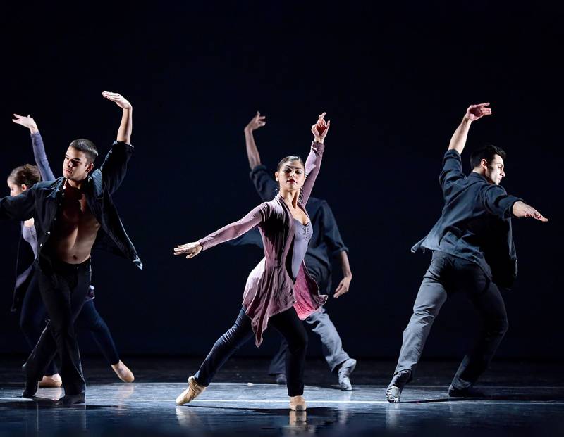 Group of male and female contemporary student dancers on stage with dramatic lighting