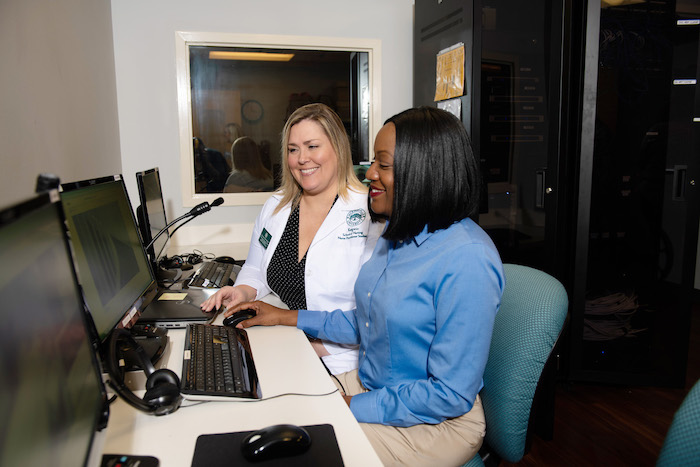 Two female healthcare professionals conferring about information on a computer.