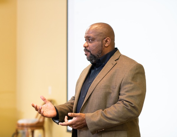 Male professor teaching in front of a classroom.