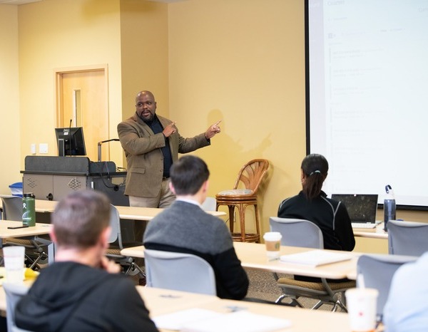 A male professor teaching students in a Davis College of Business & Technology classroom.