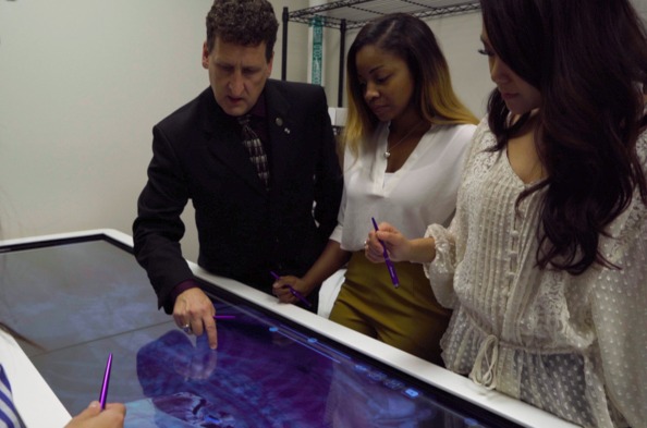 JU healthcare students and professor explore the spinal cord on an x-ray table.
