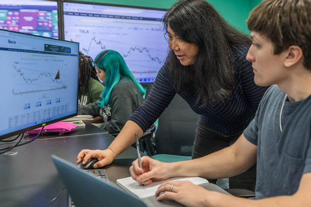 A student and faculty member working on an assignment at the computer.