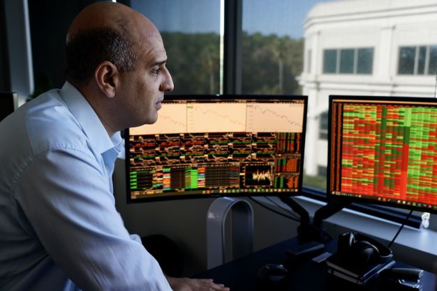 A close-up picture of an older male graduate student manipulating data at a desk with several computer monitors.