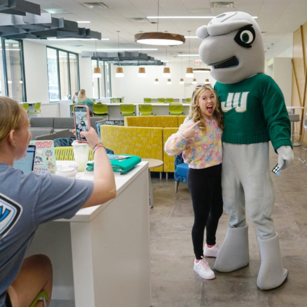 A femaie student posing for a social media selfie with JU's mascot
