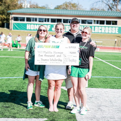 JU Student receiving their scholarship checks at Dolphin Dash 2025