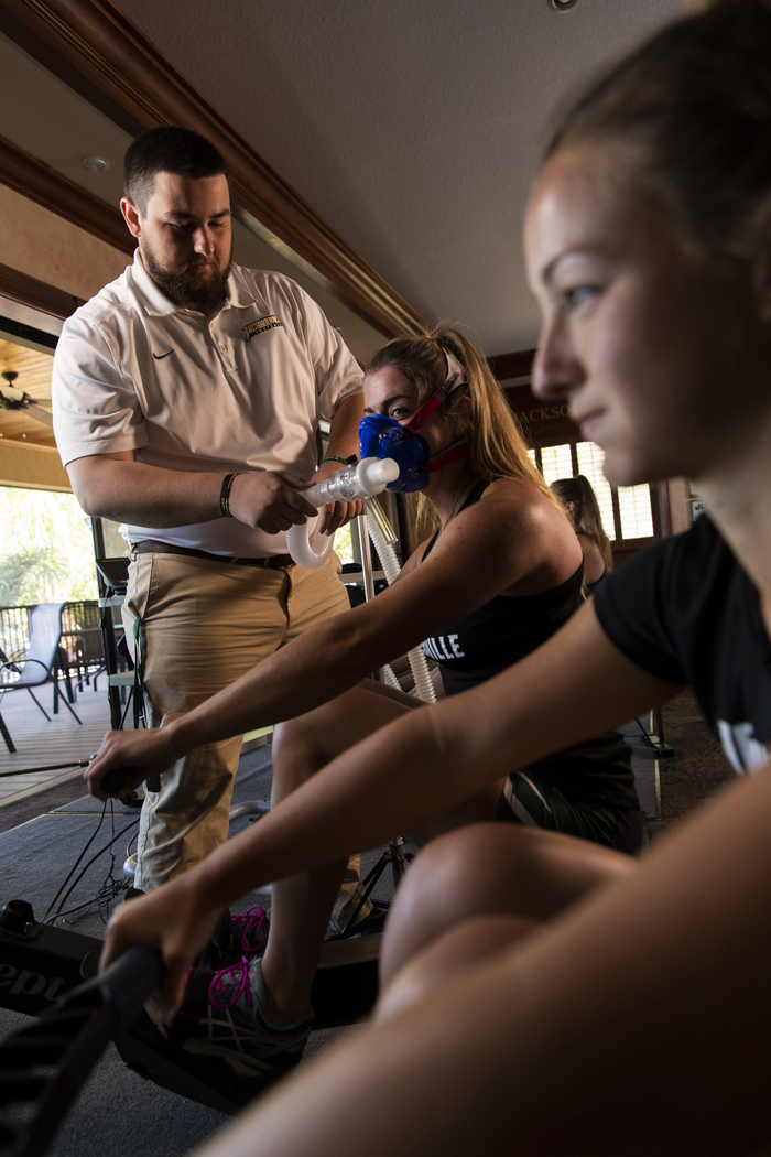 JU Rowing athlete participates in Exercise Science training simulation where she is rowing while an Exercise Science student monitors her vitals