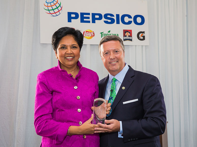 2014 honoree Indra Nooyi holding her award with President Tim Cost.