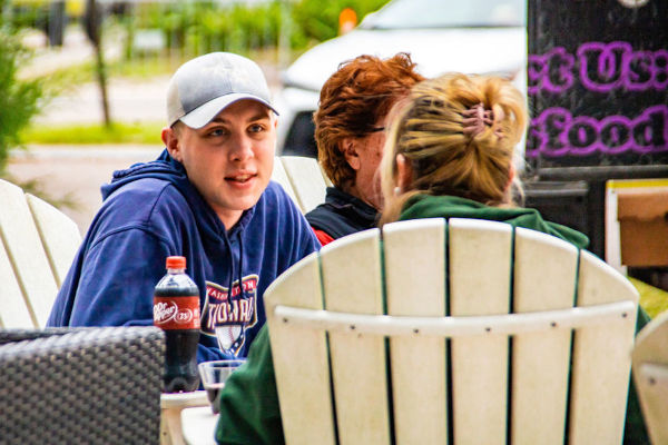 a close photo of 3 students chatting sitting on outdoor chairs