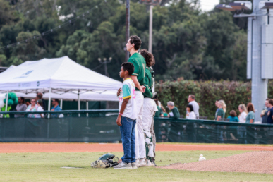 3 young students standing in the middle of a baseball field