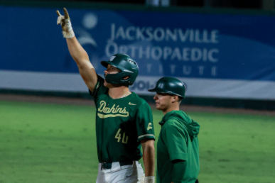 two baseball players on a field, one making the JU phins up sign with his hand