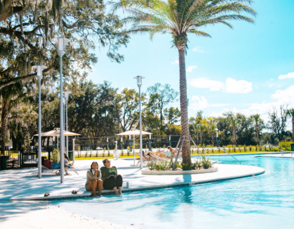Two students seating by the edge of a swimming pool.