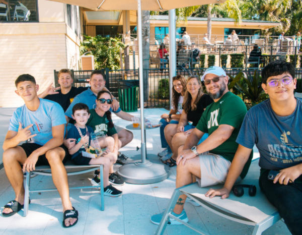 A group of parents and students seating outdoors around a picnic table.