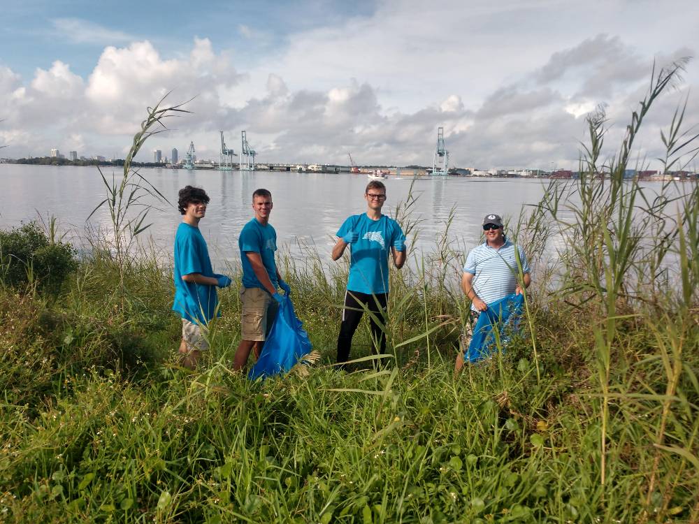 Four male honor volunteers cleaning up the marshes.